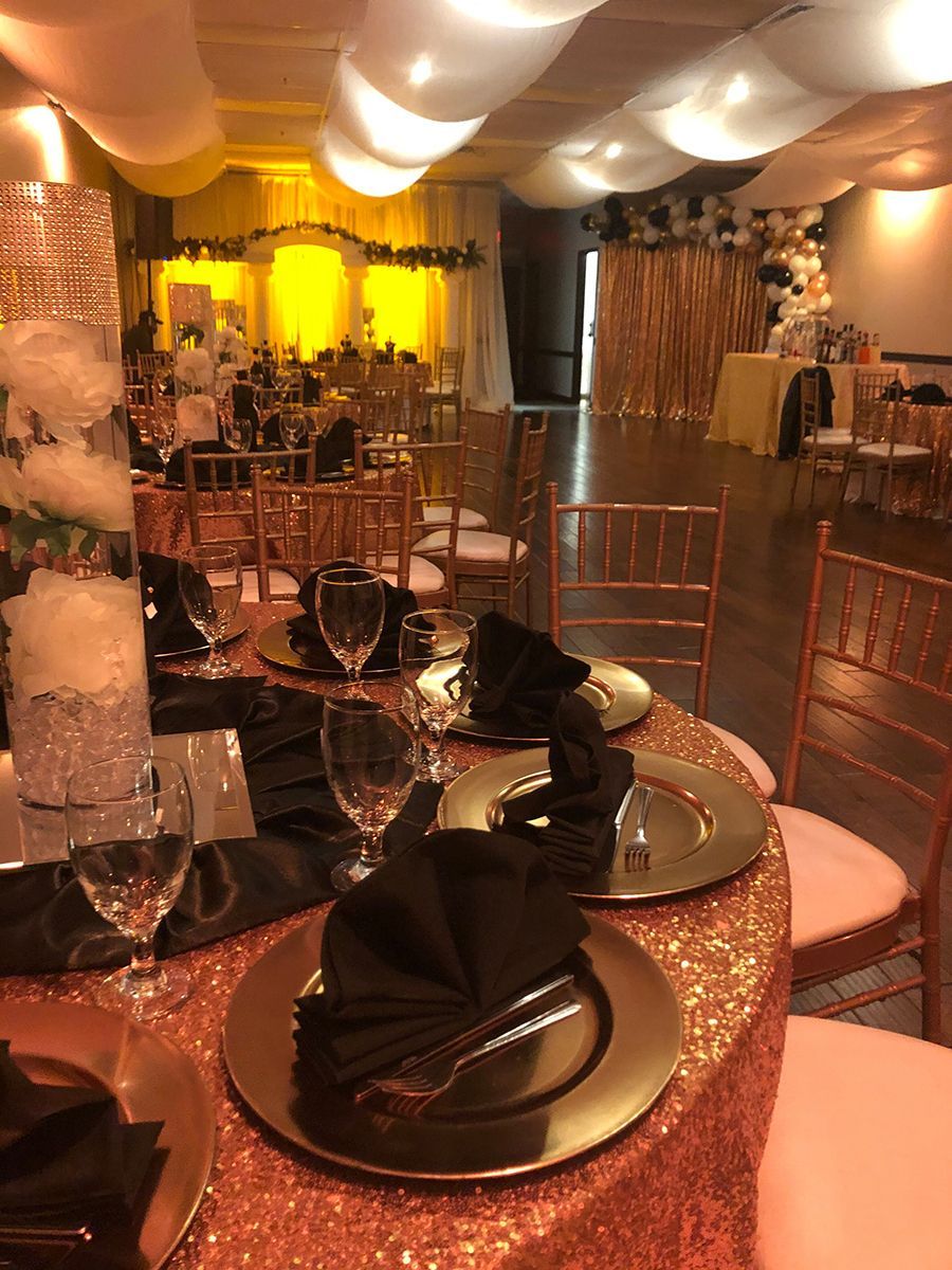 Formal event space with decorated tables, gold accents, and a yellow backdrop.