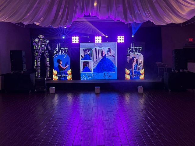 Stage setup for an event, featuring a large photo display, lighting, and robot figures. Purple lighting illuminates the scene.