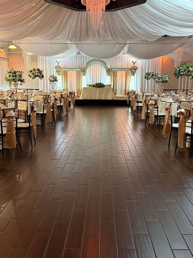 Ballroom set for an event with a stage, tables, chairs, and draping.