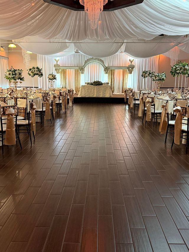 Ballroom set for an event with a stage, tables, chairs, and draping.