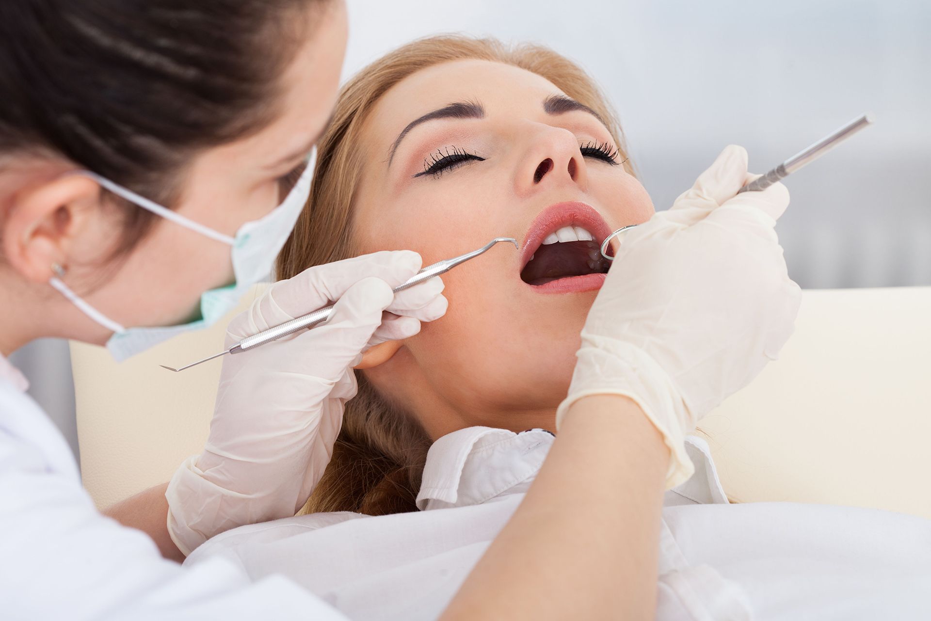 A woman is getting her teeth examined by a dentist.