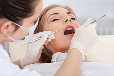 A woman is getting her teeth examined by a dentist.