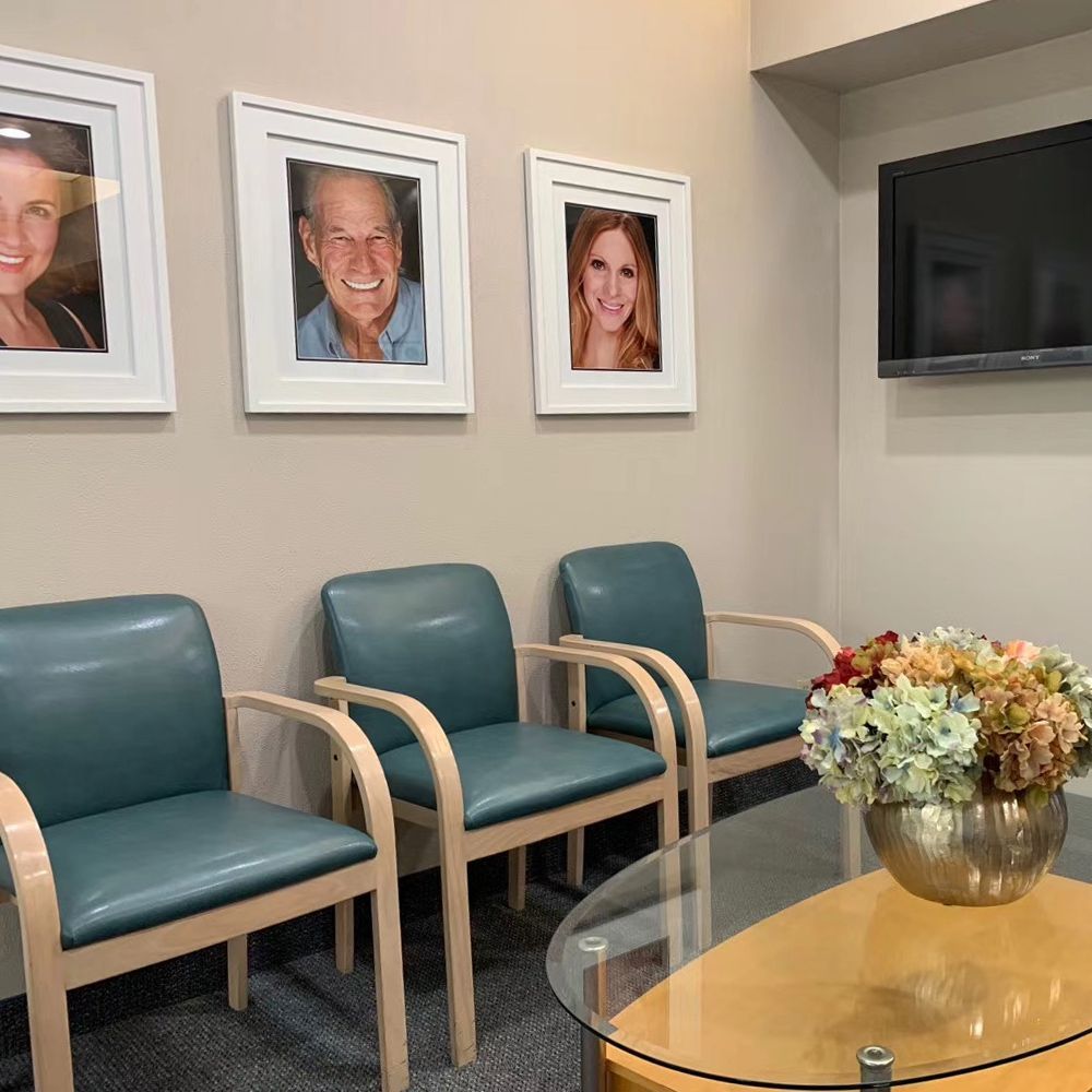 A waiting room with chairs, a table, and pictures on the wall.