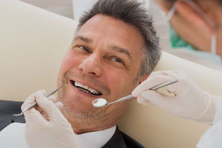 A man is having his teeth examined by a dentist.