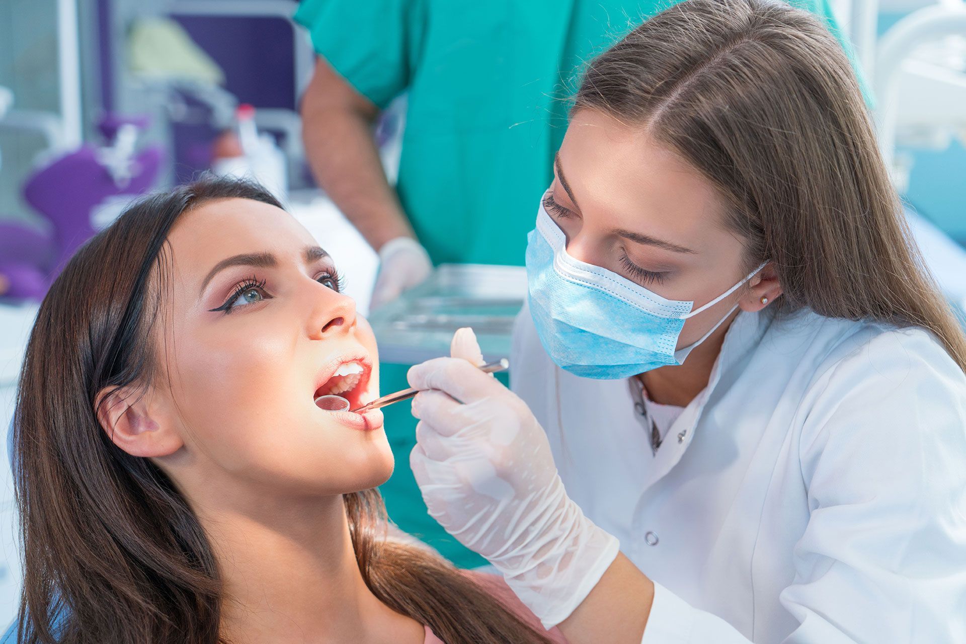 A woman is getting her teeth examined by a dentist in a dental office.