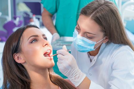 A woman is getting her teeth examined by a dentist in a dental office.