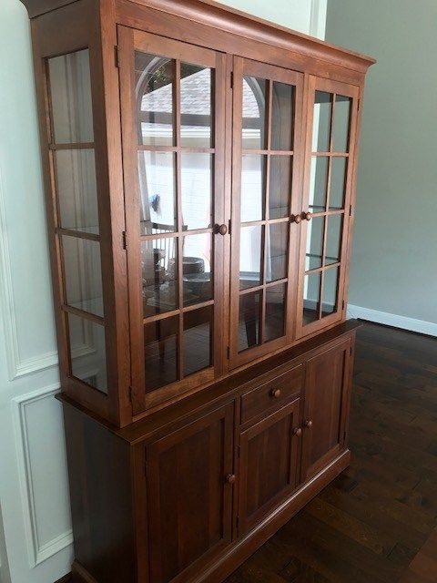 A wooden hutch with glass doors in a dining room