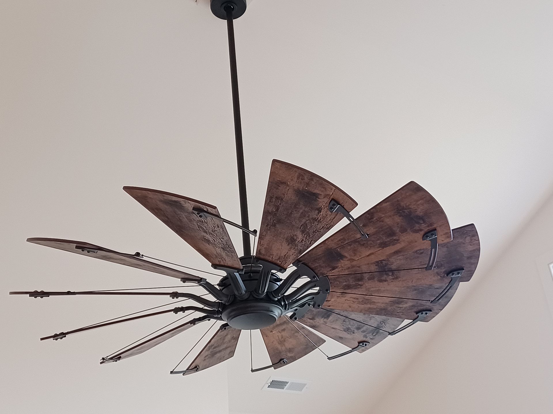 Rustic metal ceiling fan with weathered brown blades against a white ceiling