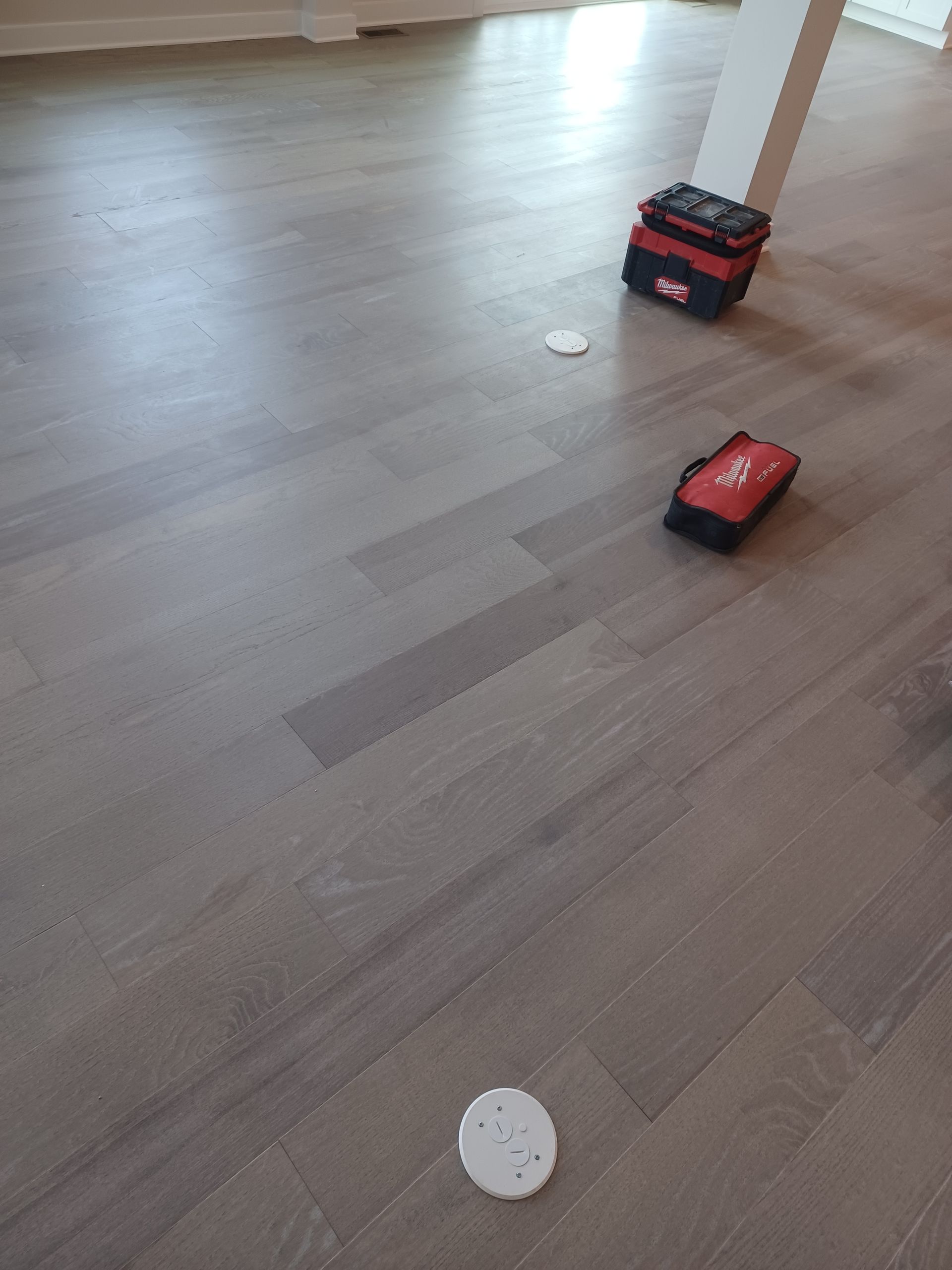Toy trucks on a wooden floor near a white column.