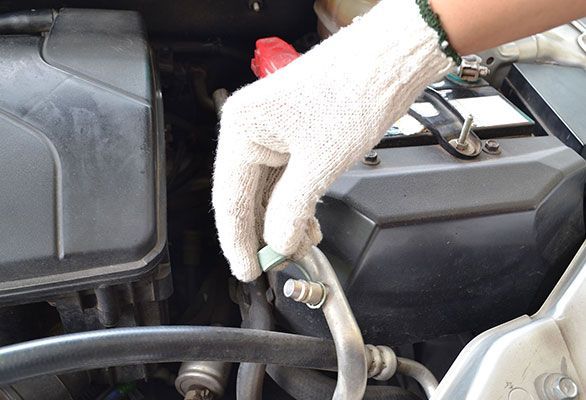 A person wearing white gloves is working on a car