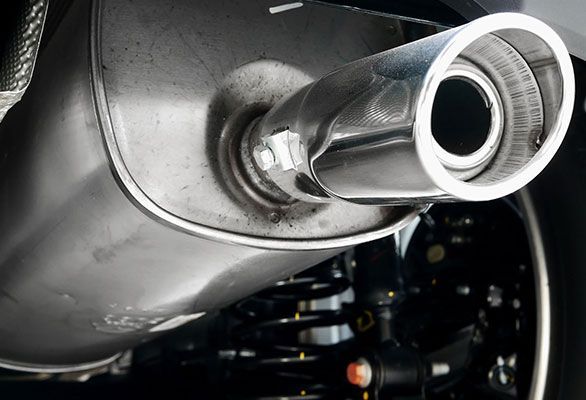 A close up of a stainless steel exhaust pipe on a car.