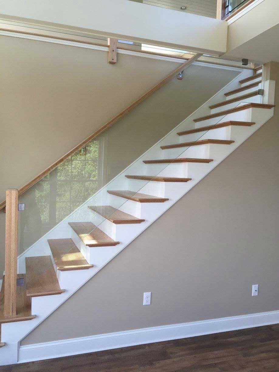 Staircase with wooden steps and railing, glass panels, white accents, against a beige wall.
