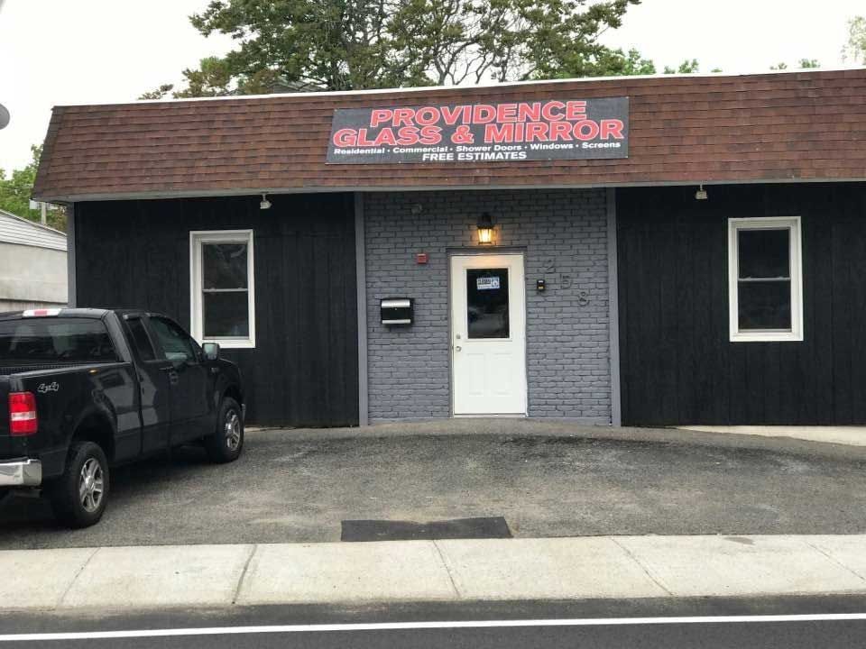 Providence Glass & Mirror storefront with black truck parked in front. Black building, brown roof.
