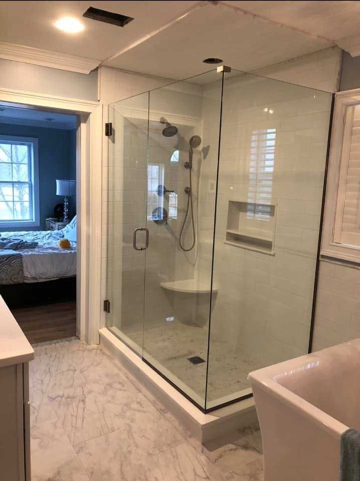 Modern bathroom with glass shower enclosure, marble tile, and white walls.