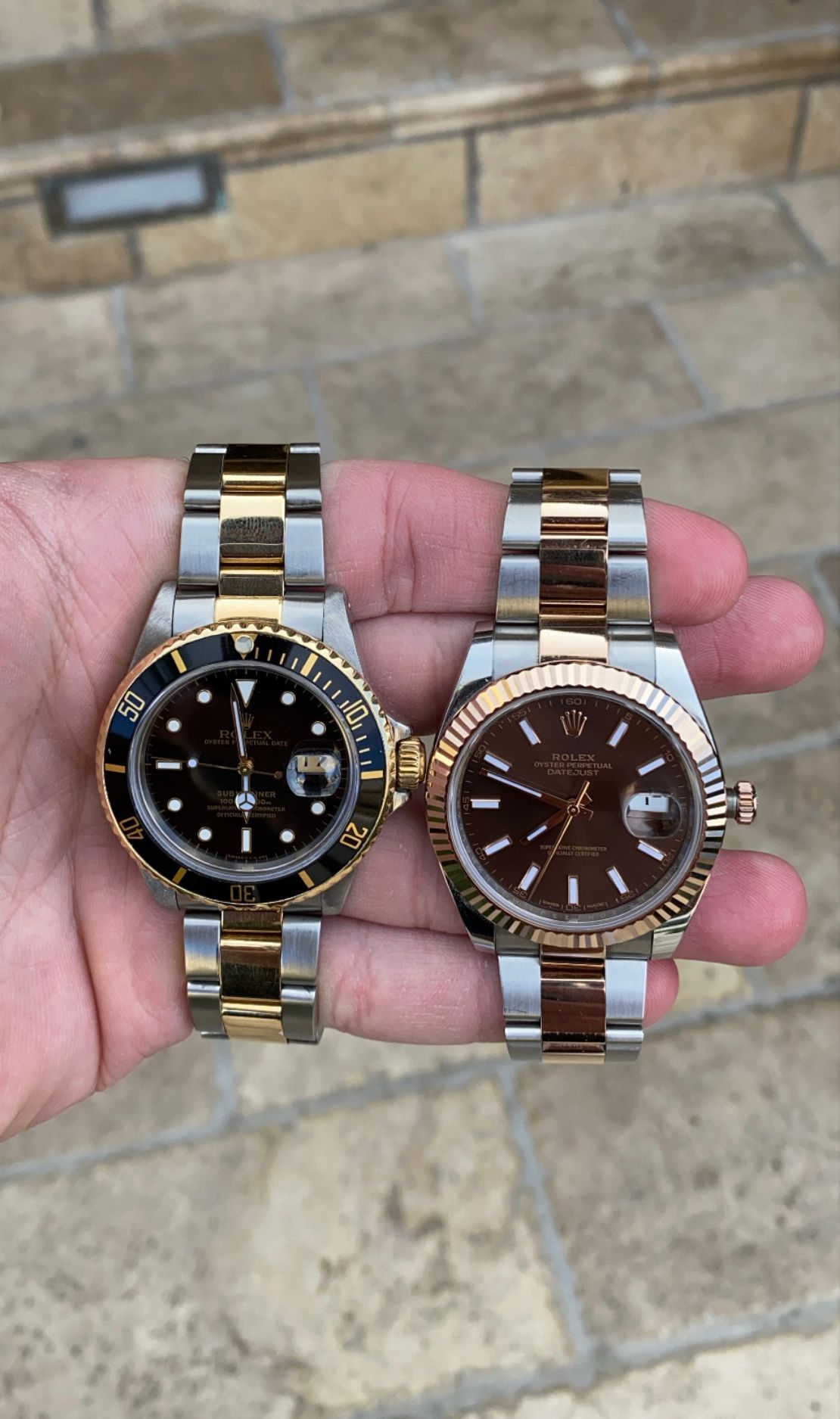 A person is holding two rolex watches in their hand.