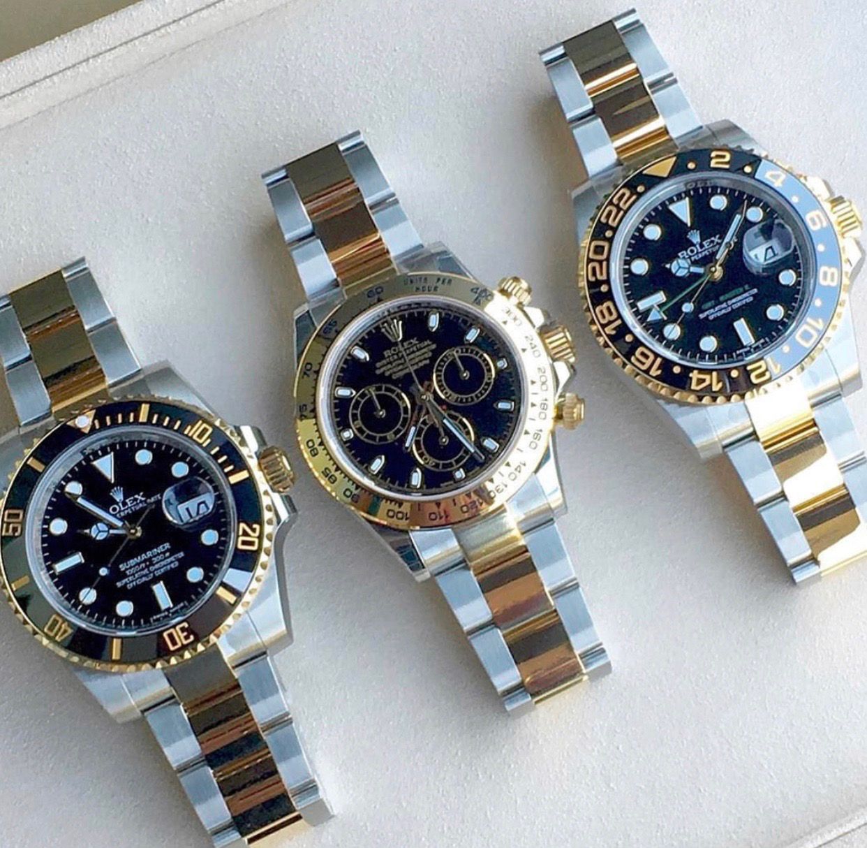 Three rolex watches are sitting on a white surface