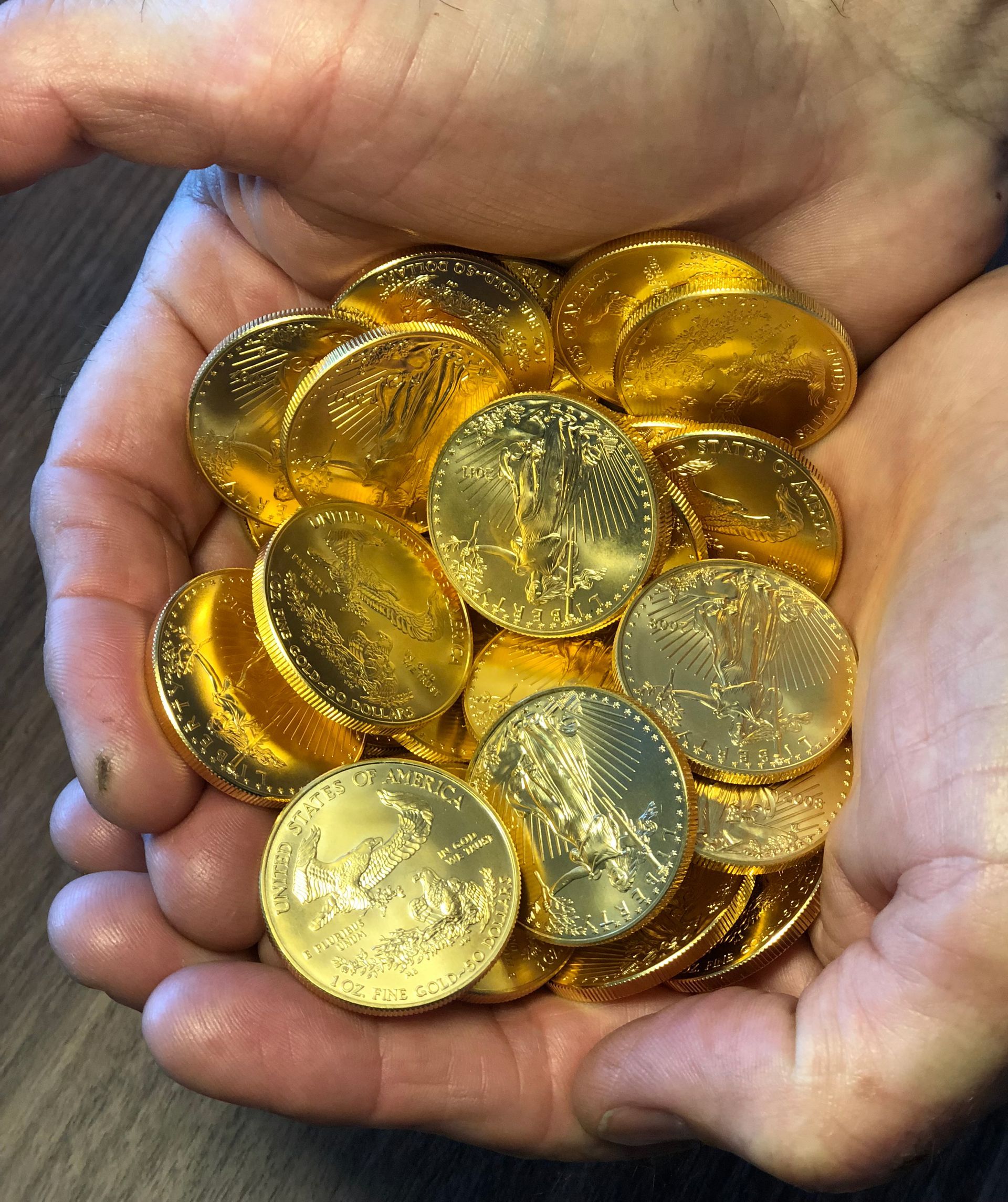A person is holding a pile of gold coins in their hands