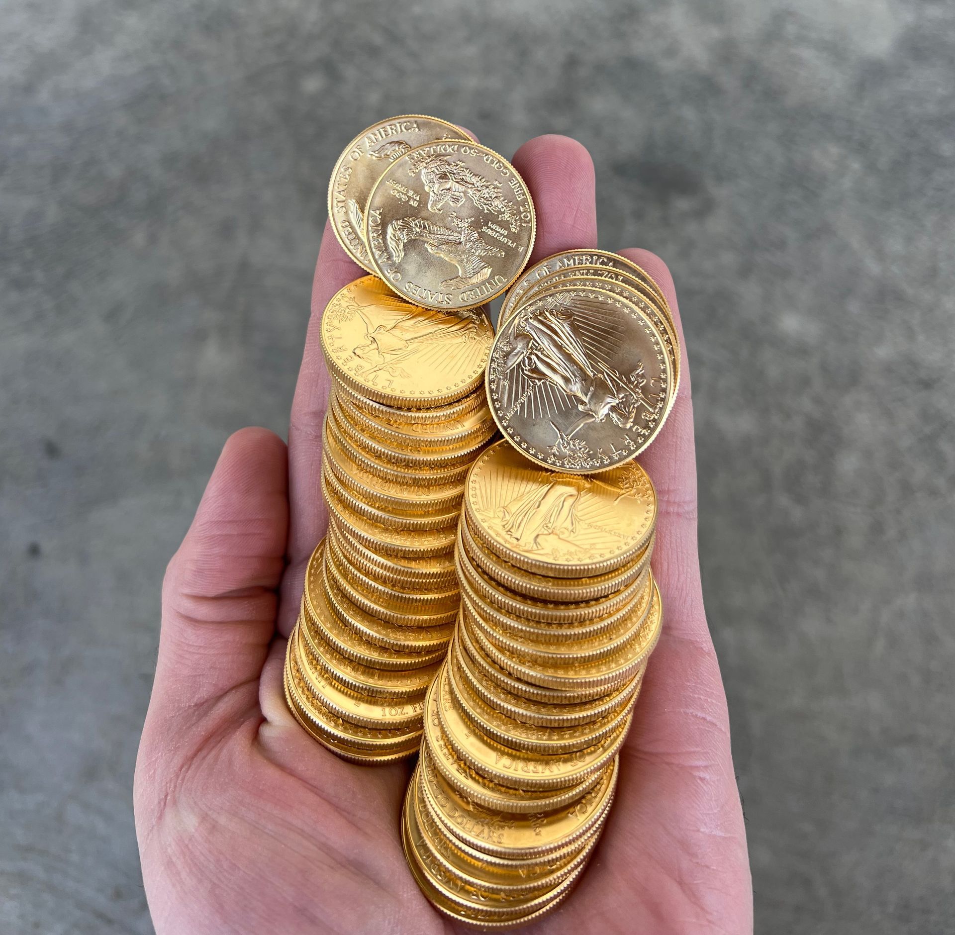 A hand is holding a pile of gold coins