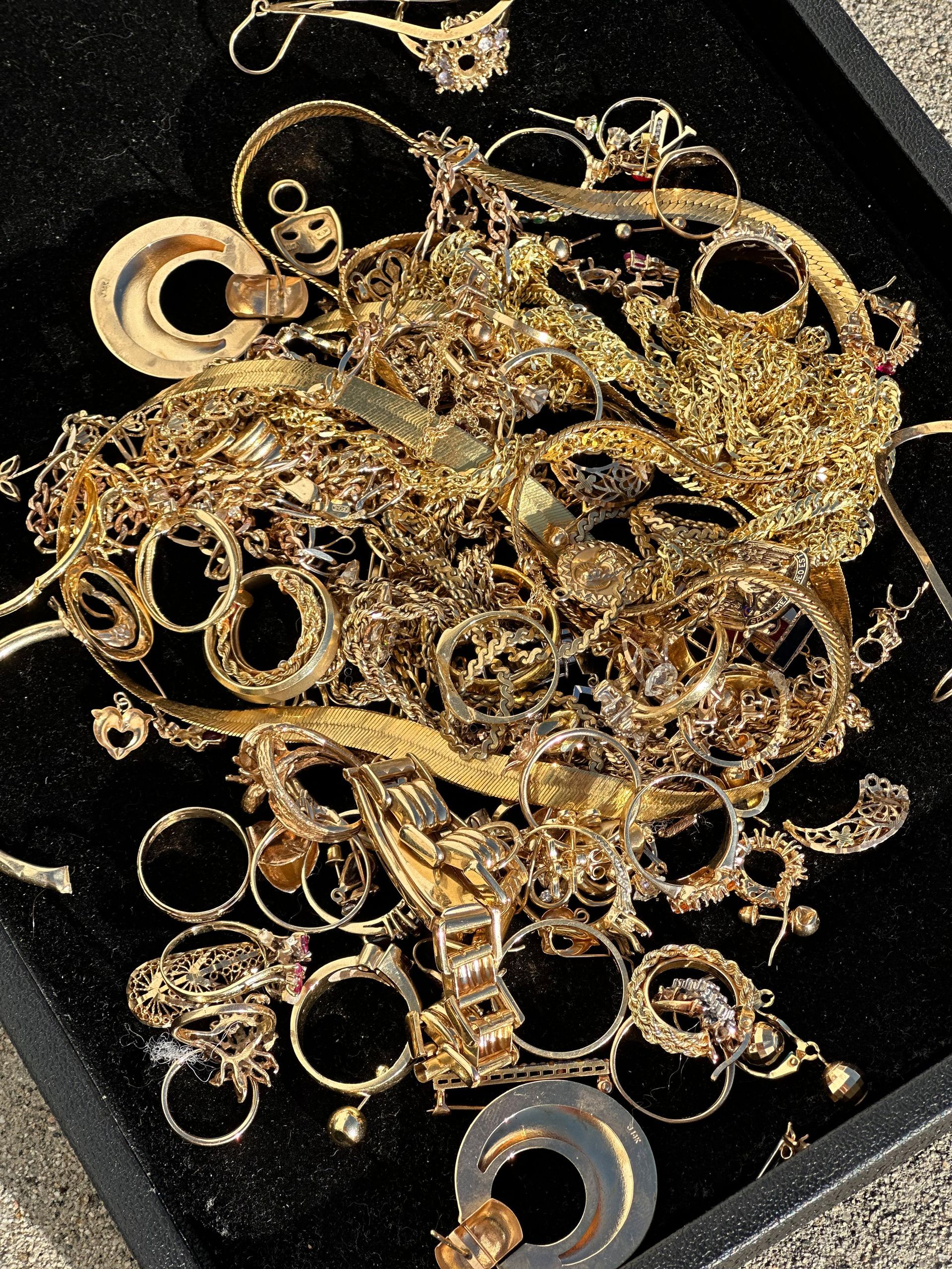A pile of gold jewelry is sitting on a black tray.