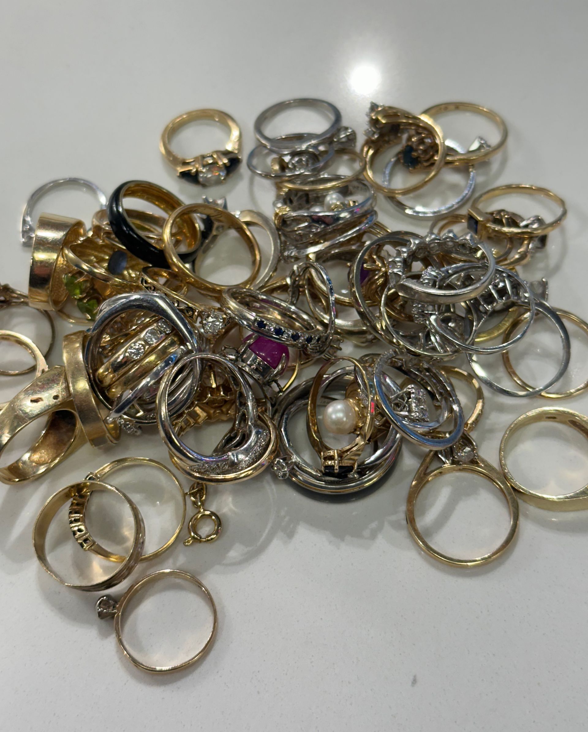 A pile of gold and silver rings on a white surface