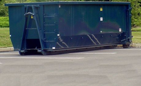 A large blue dumpster is parked in a parking lot.