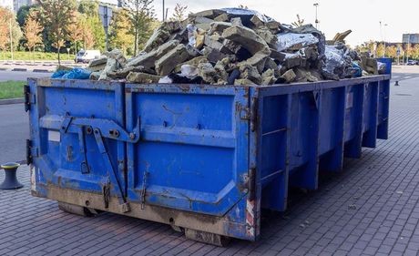 A blue dumpster filled with concrete.