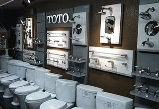 A showroom displays TOTO toilets and bathroom fixtures, including faucets, showerheads, and towel racks.