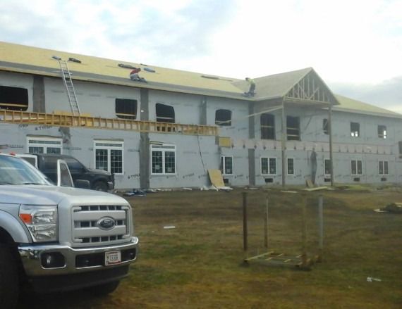 Partly built white building with scaffolding and a silver pickup truck in the foreground