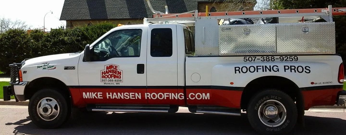 White roofing pros pickup truck with ladder rack and company logo parked on a street