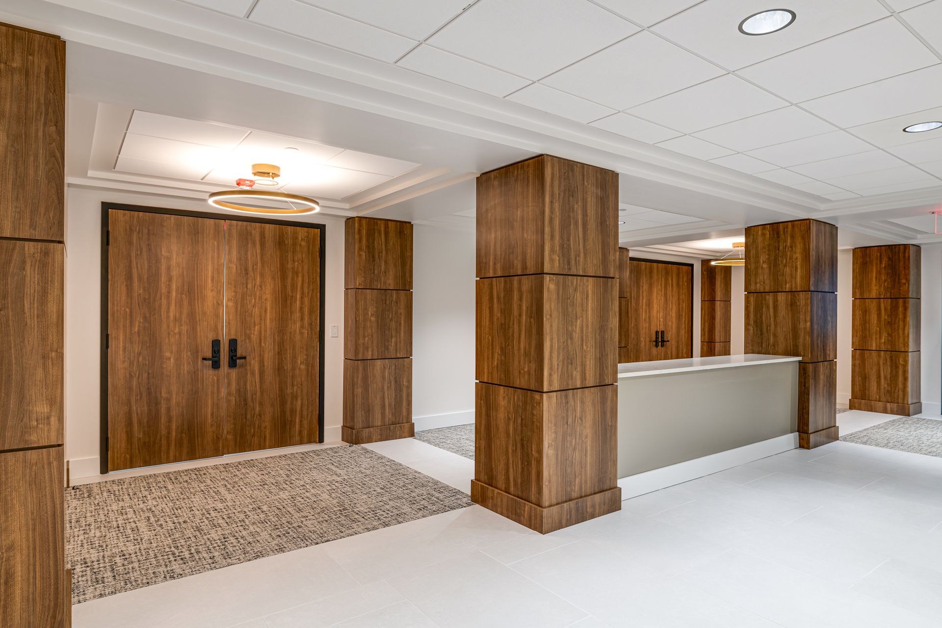 A hallway with wooden doors and columns and a reception desk.