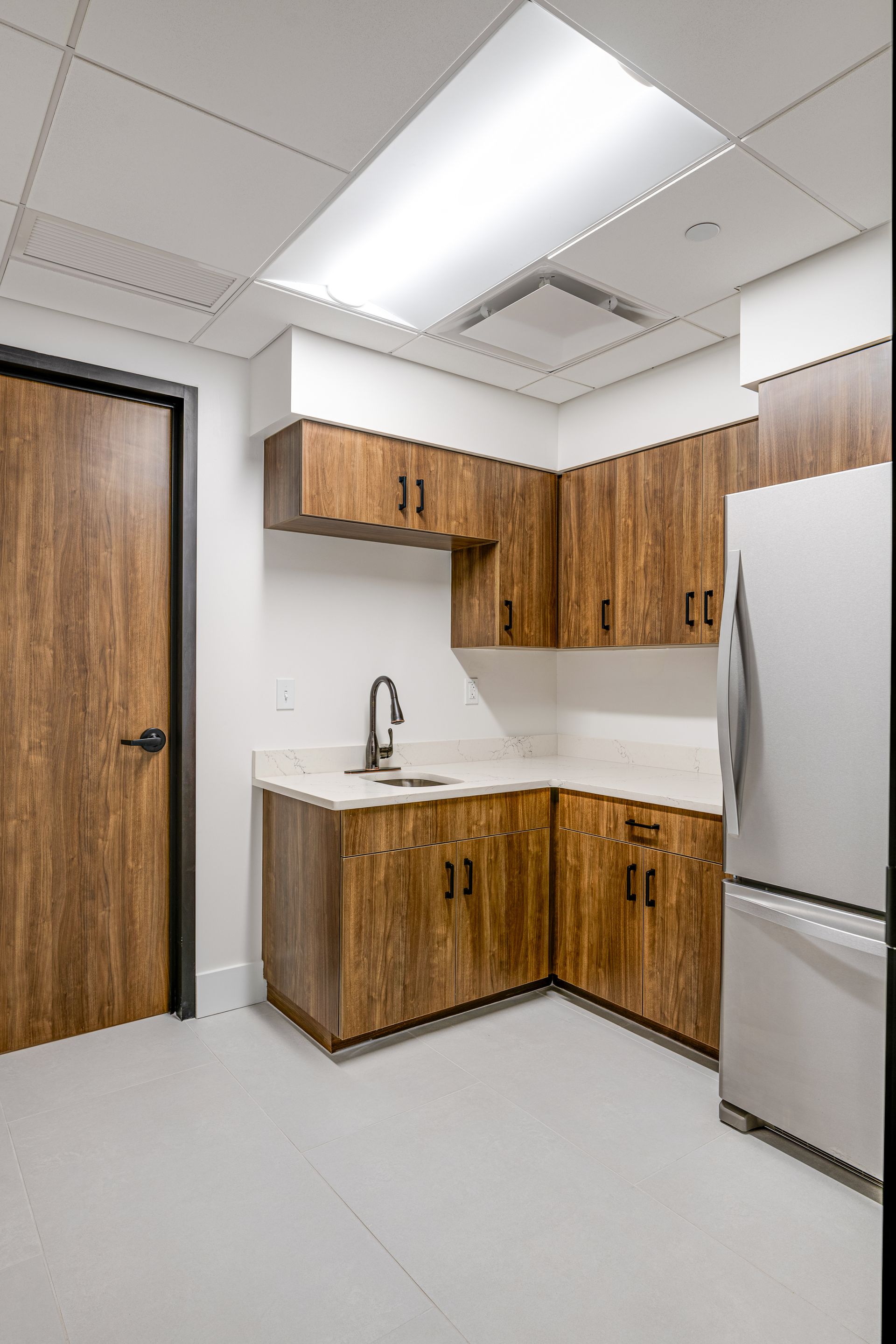 A kitchen with wooden cabinets, a sink, and a refrigerator.