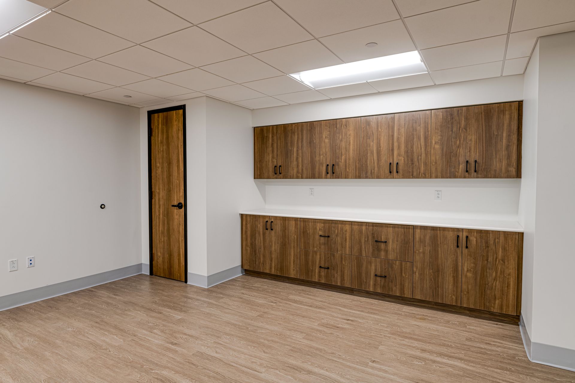 An empty room with wooden cabinets and a door.