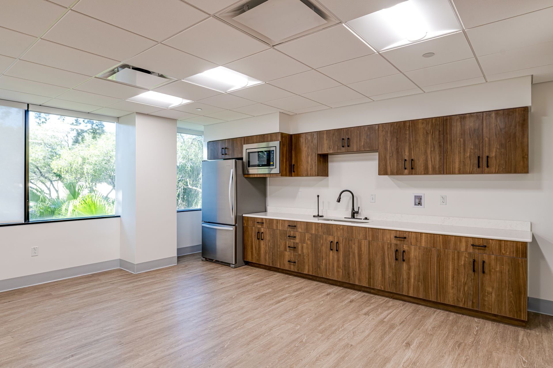 An empty kitchen with wooden cabinets and stainless steel appliances.