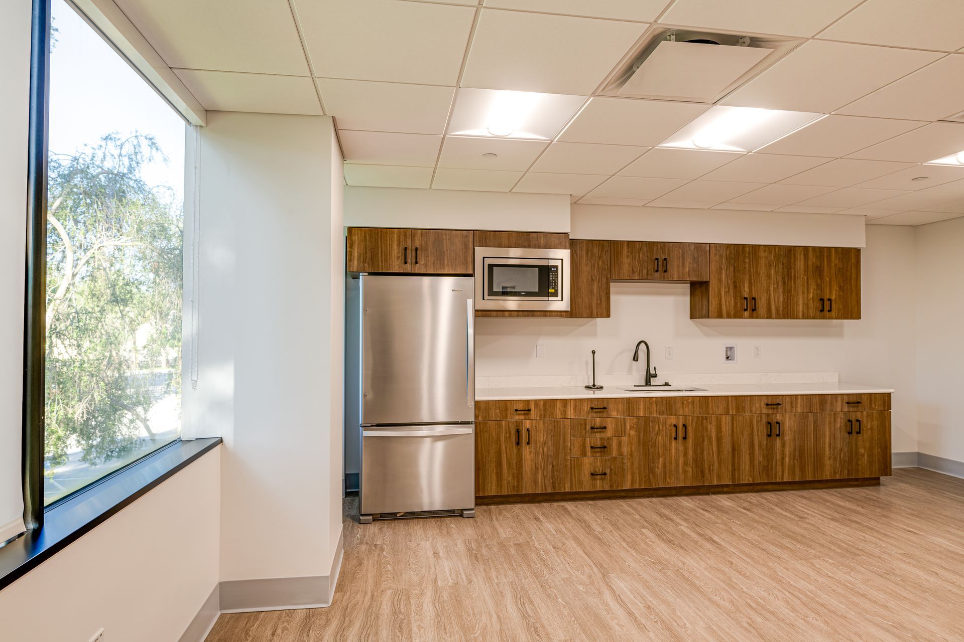 An empty kitchen with stainless steel appliances and wooden cabinets.