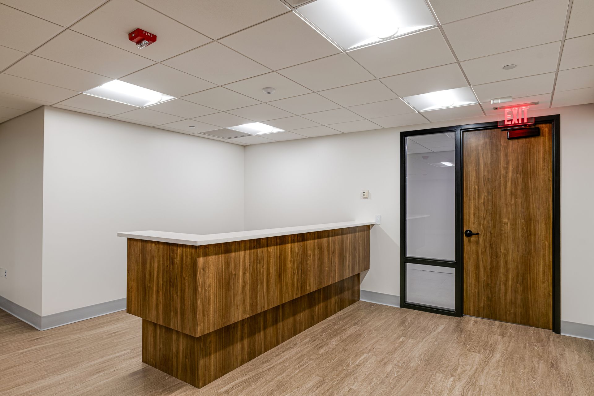 An empty room with a wooden desk and a door.