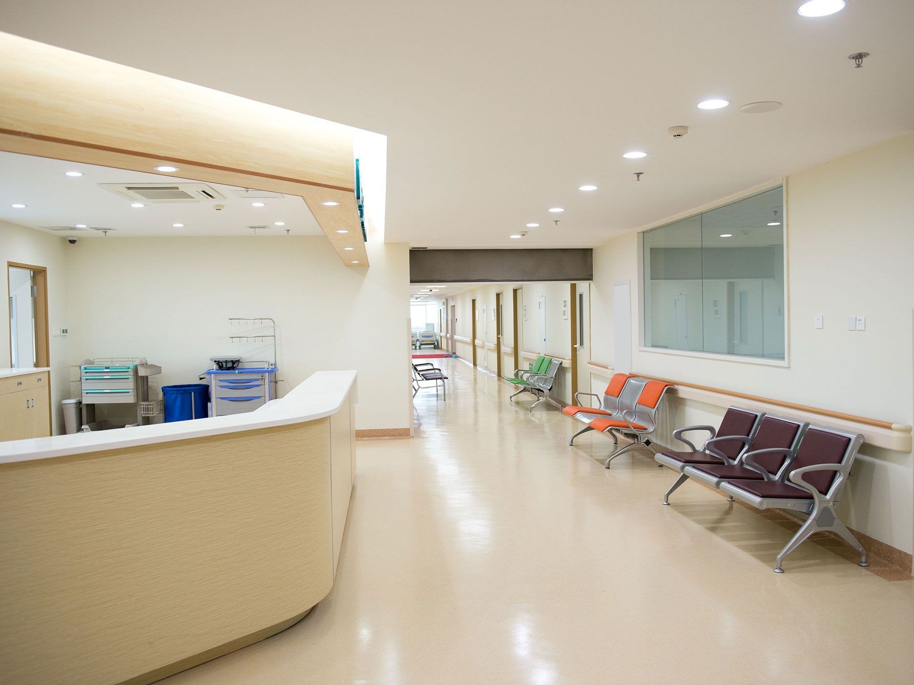 A hospital hallway with a reception desk and chairs.