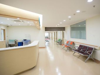 A hospital hallway with a reception desk and chairs.