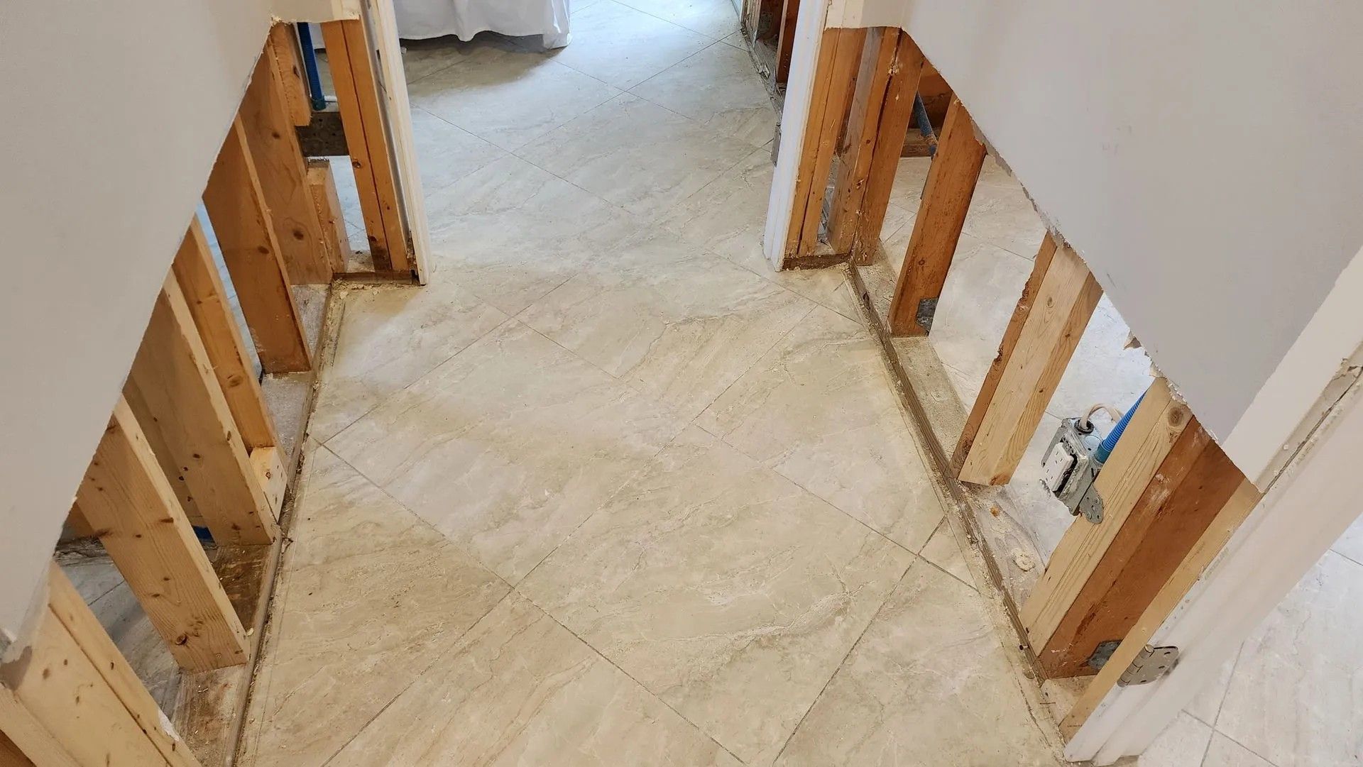 Hallway under construction with exposed wooden frames and tile flooring.