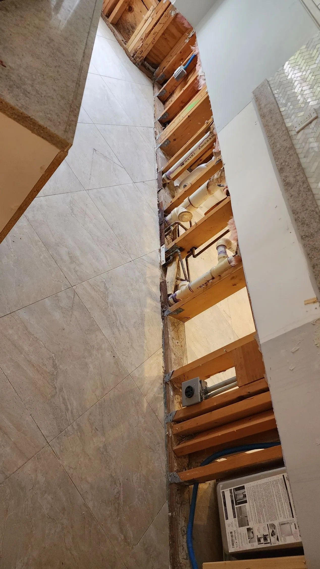 Narrow vertical space between two walls revealing wooden structures and some objects.