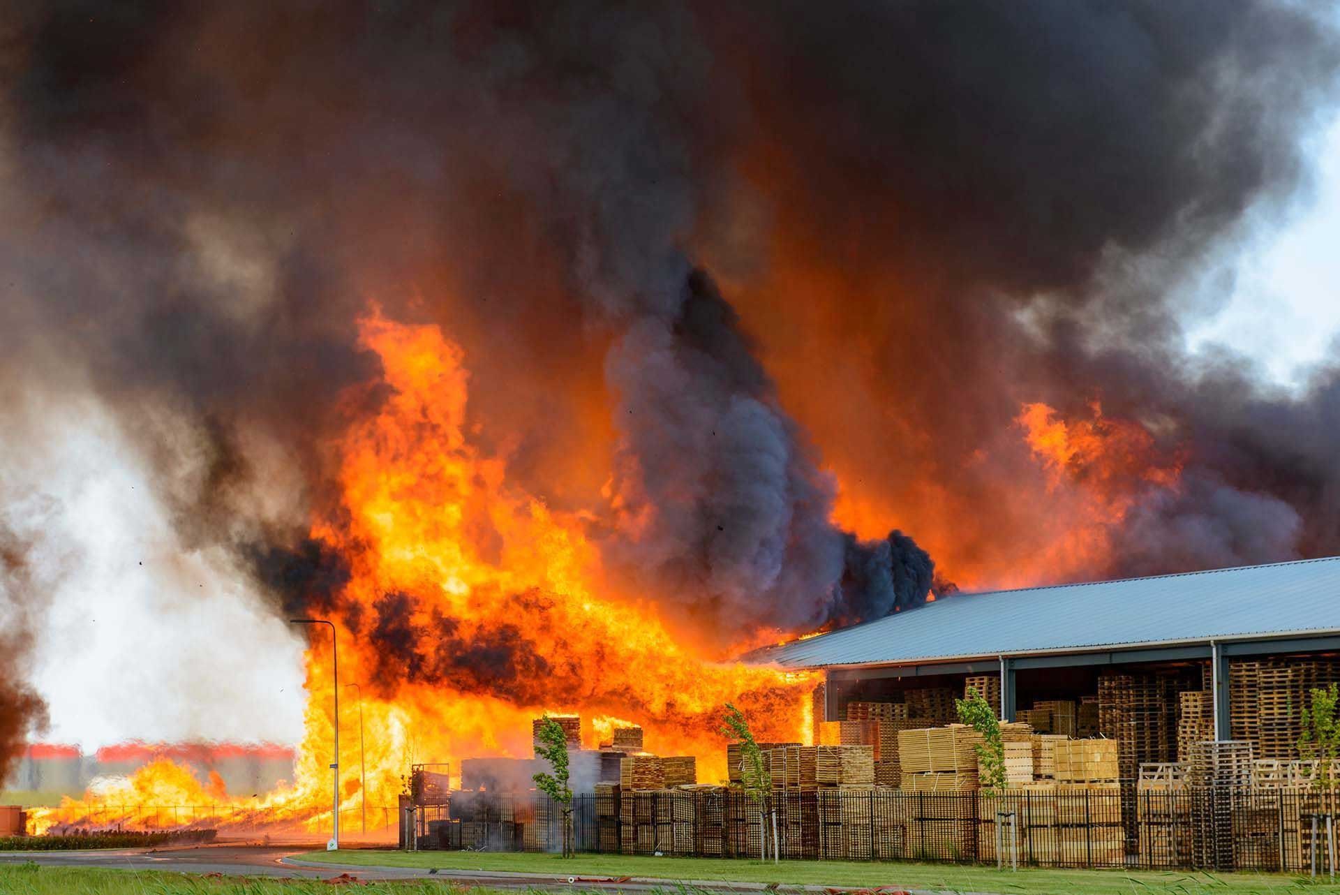 Building engulfed in flames with thick black smoke billowing into the sky.