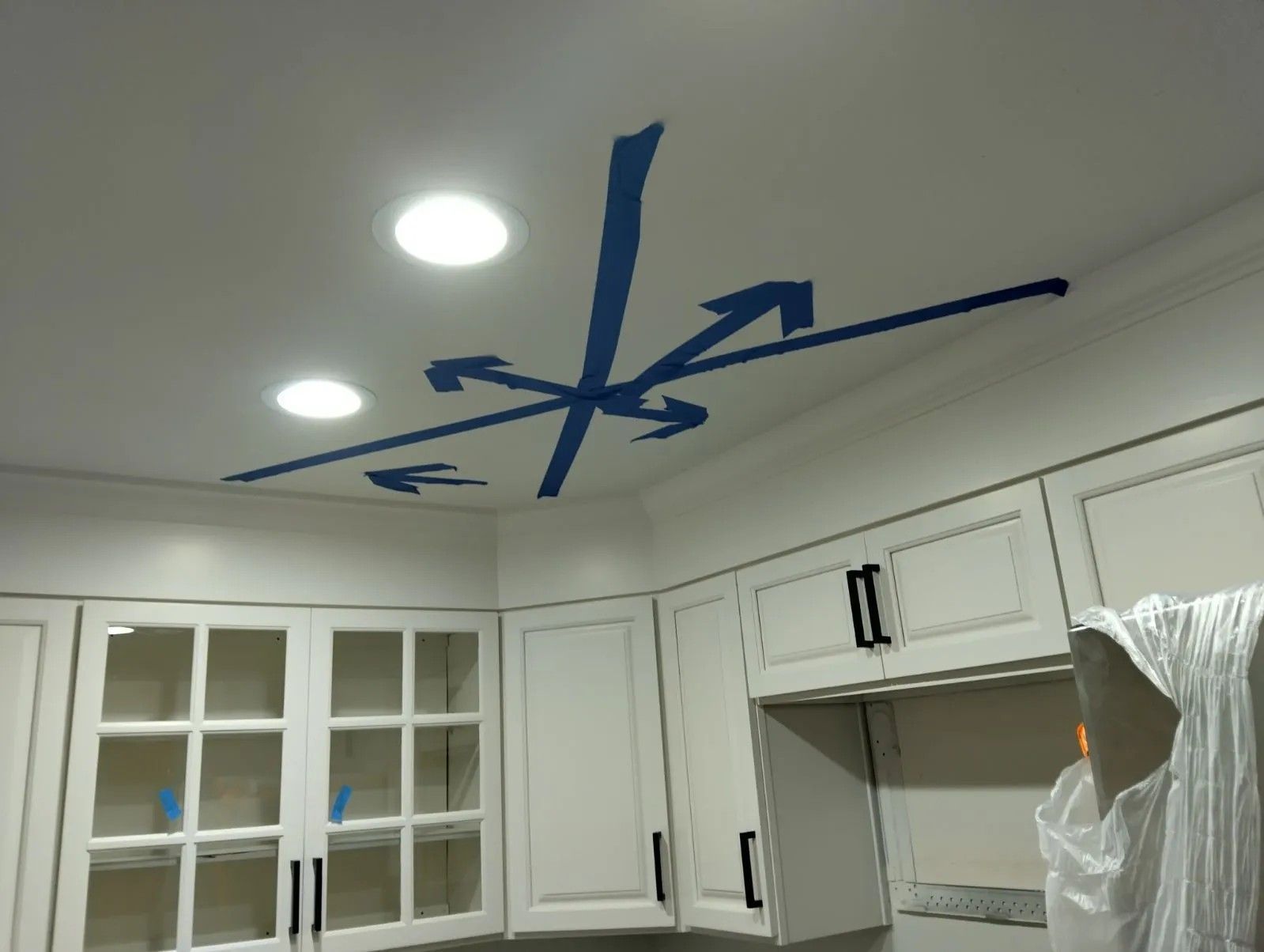 White kitchen with arrows pointing to the ceiling and recessed lighting, indicating airflow.
