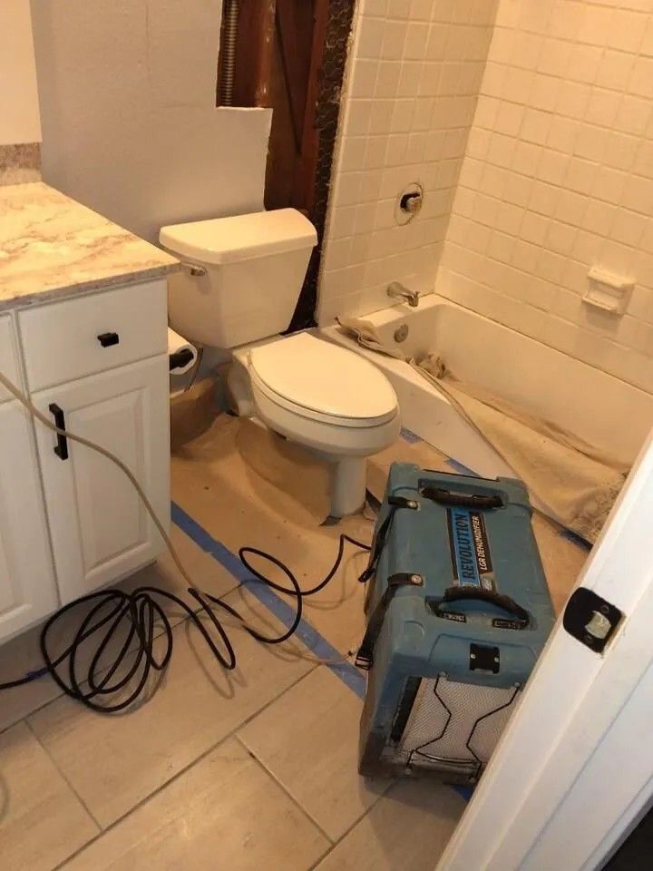 Bathroom with a toilet, vanity, and a moisture removal device, likely after water damage.