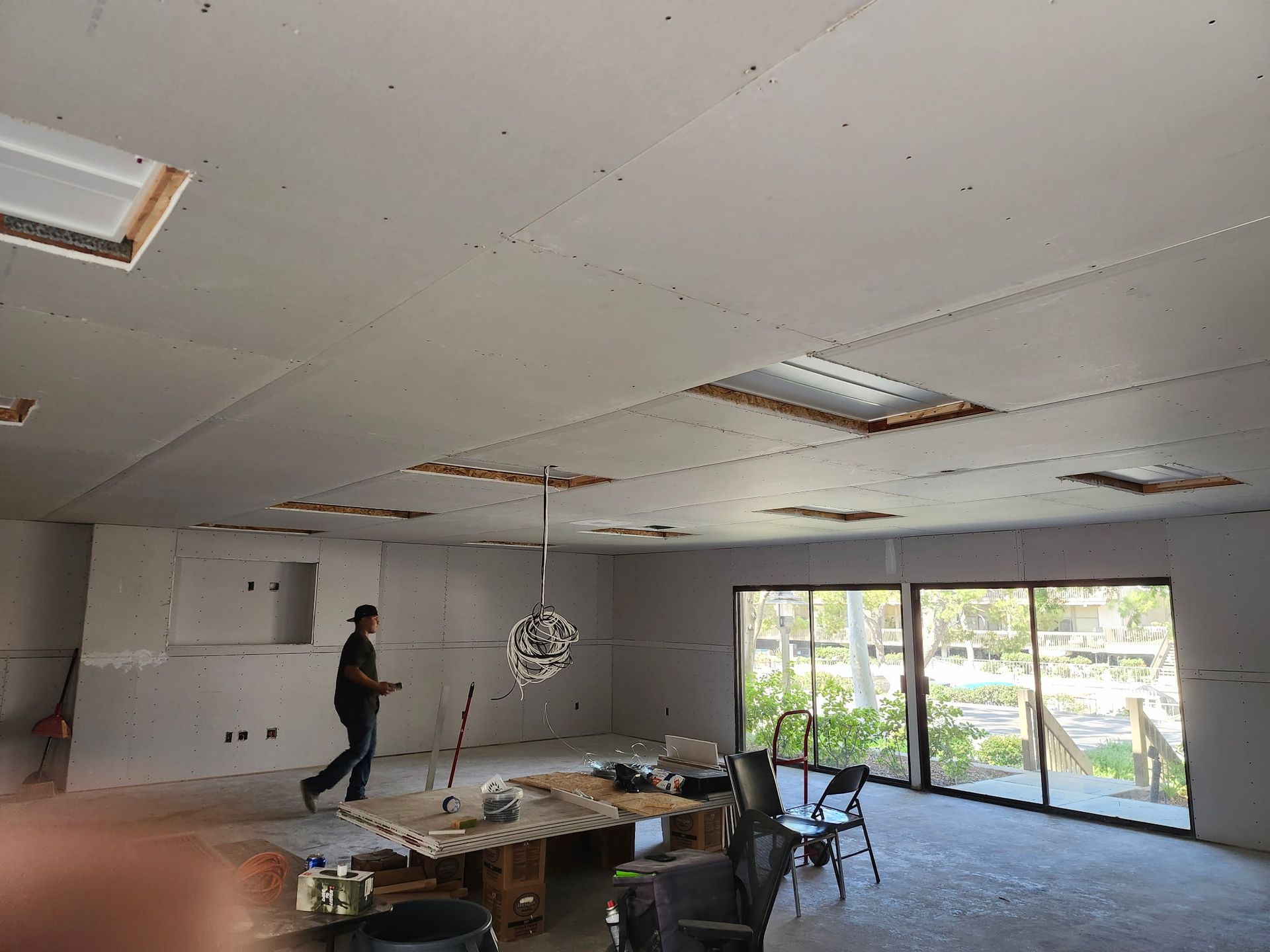 Room under construction with drywall and a person walking.
