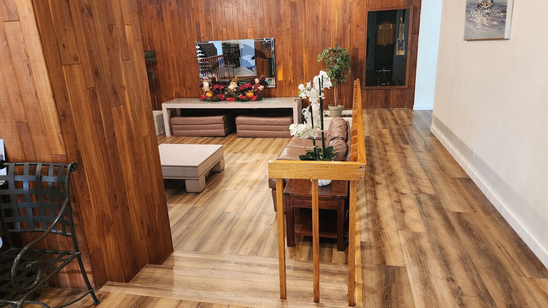 Wooden-paneled interior with a table, sofa, and décor. Floors are wood-look.