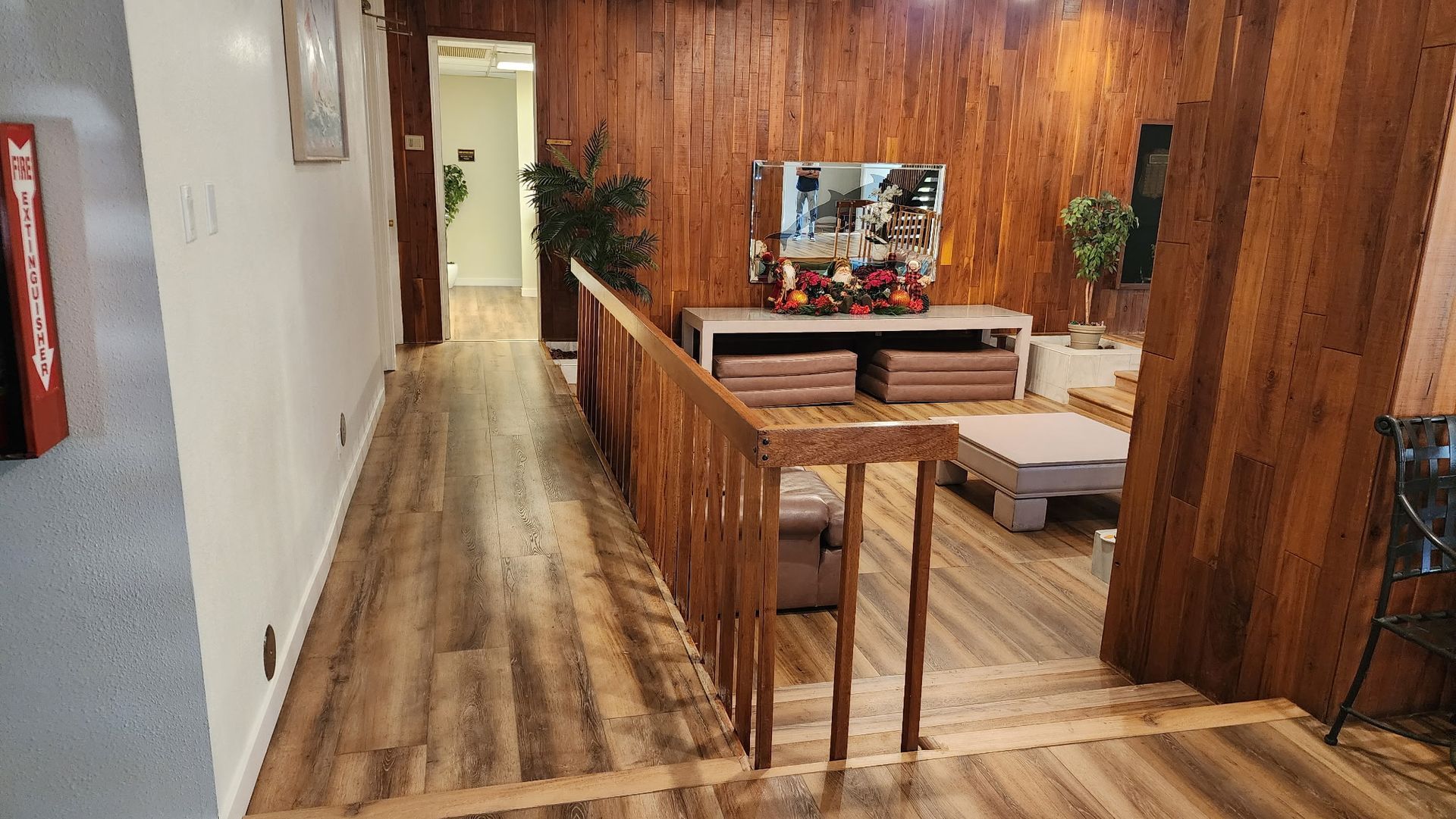 Hallway with wood paneling, staircase, and living room area with furniture.
