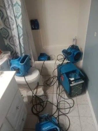 Blue water damage restoration equipment in a bathroom.