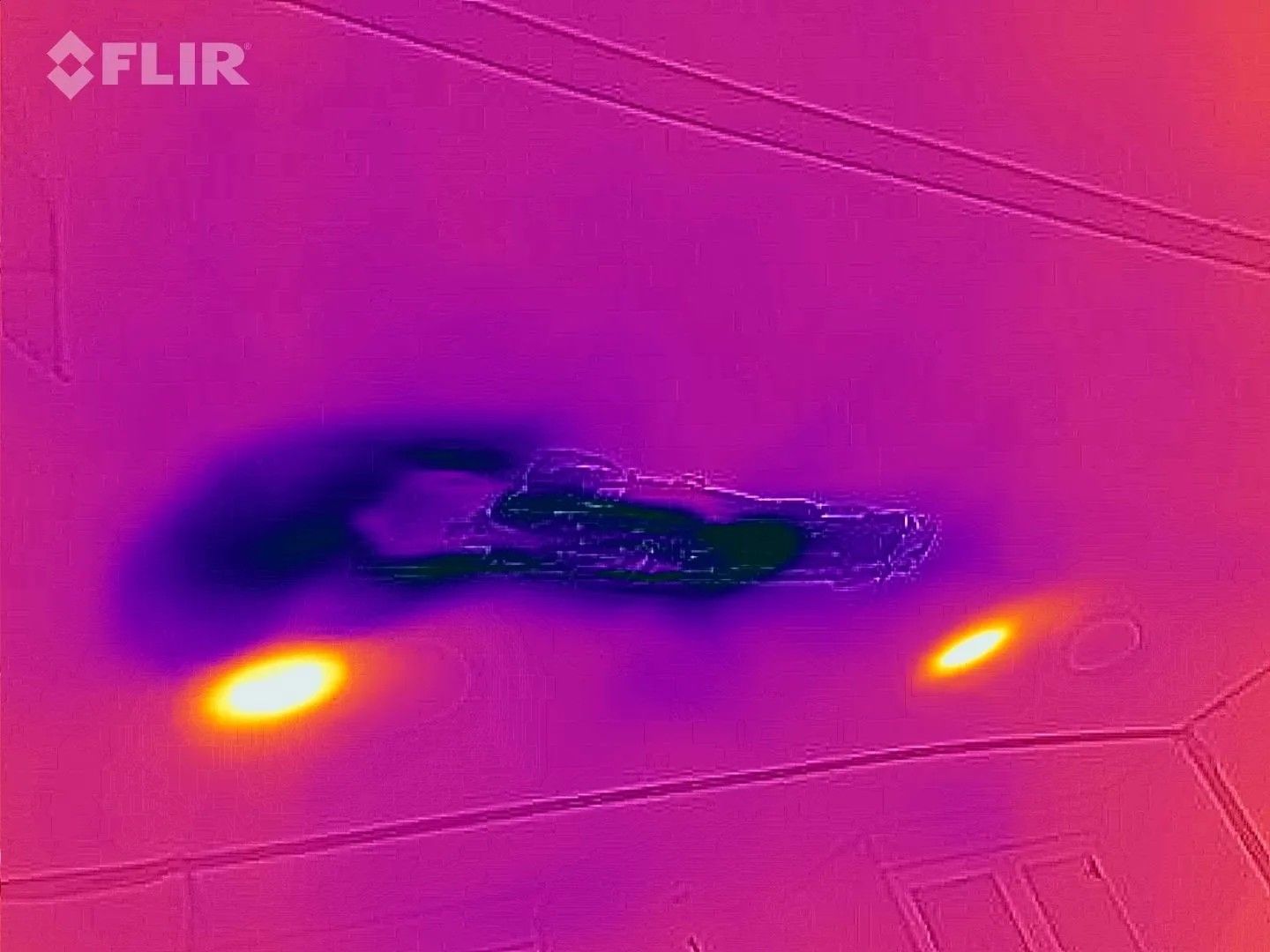 Thermal image of ceiling with dark, cold water damage and two warm lights.