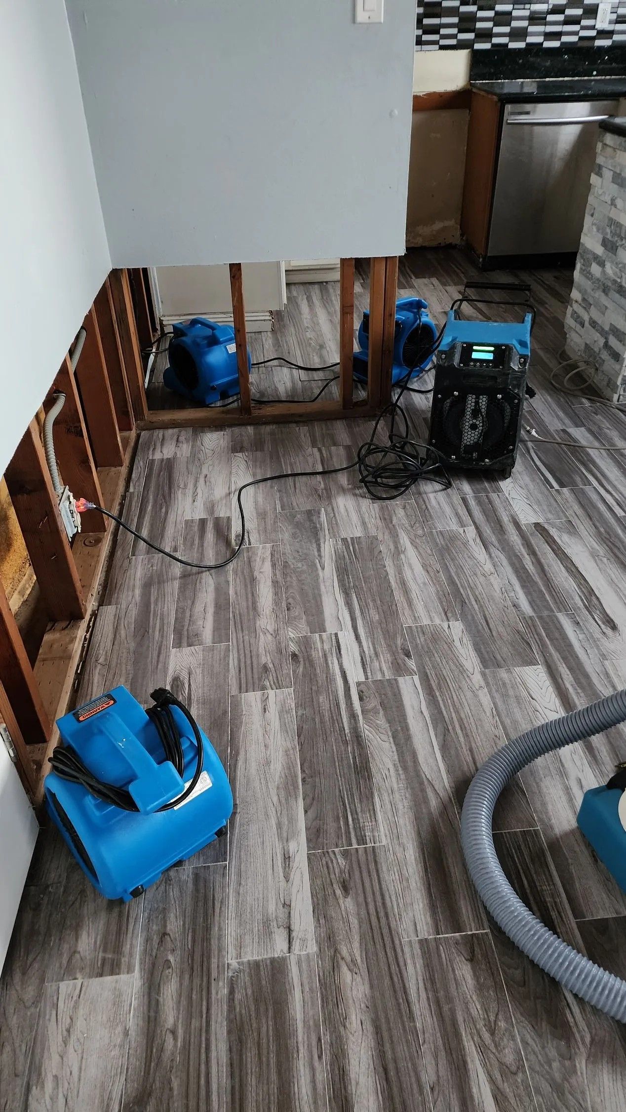 Flood damage restoration in a home. Equipment on the floor and open wall cavity drying the affected area.