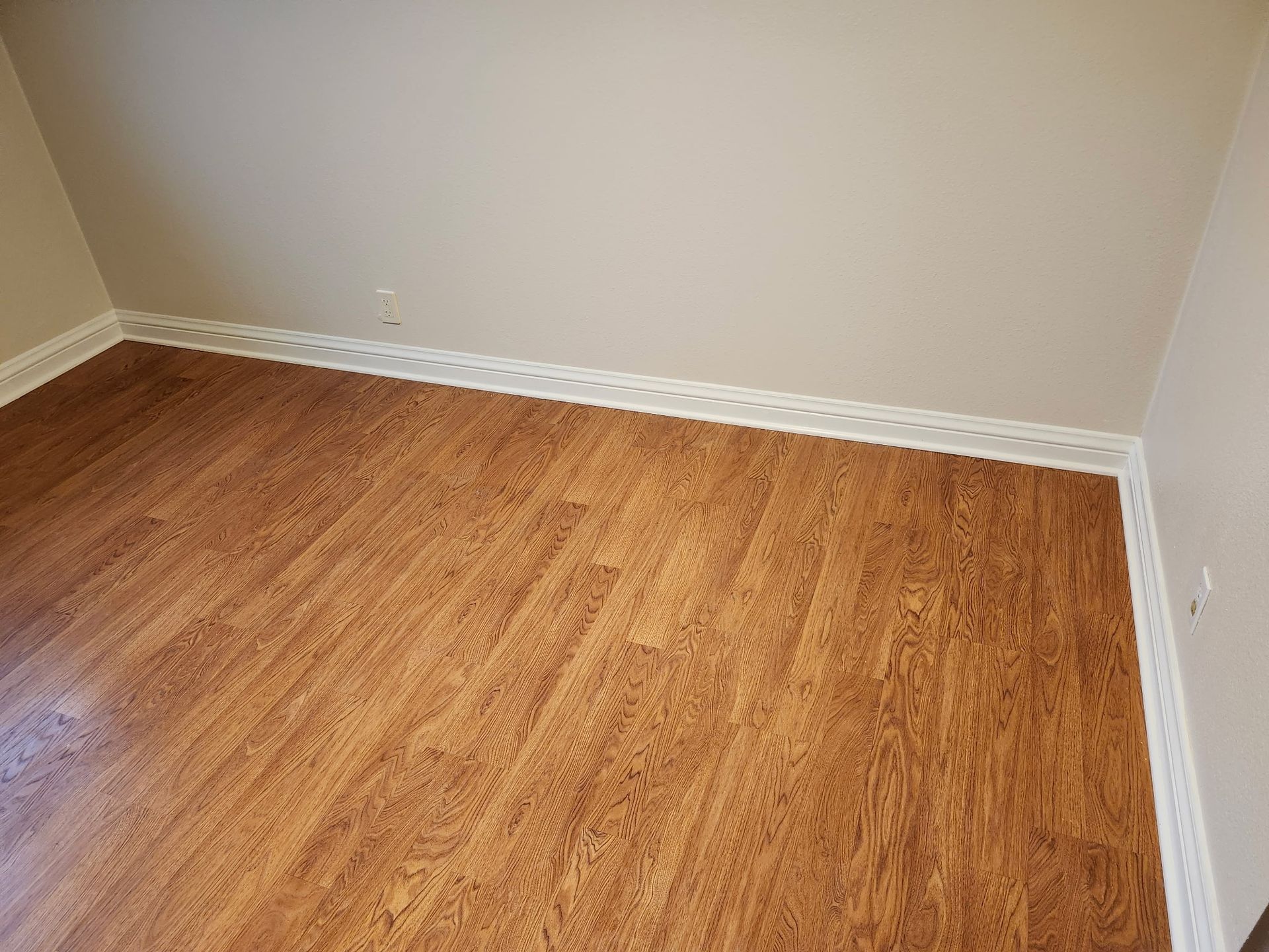 Room with cork flooring, beige walls, and white baseboards.