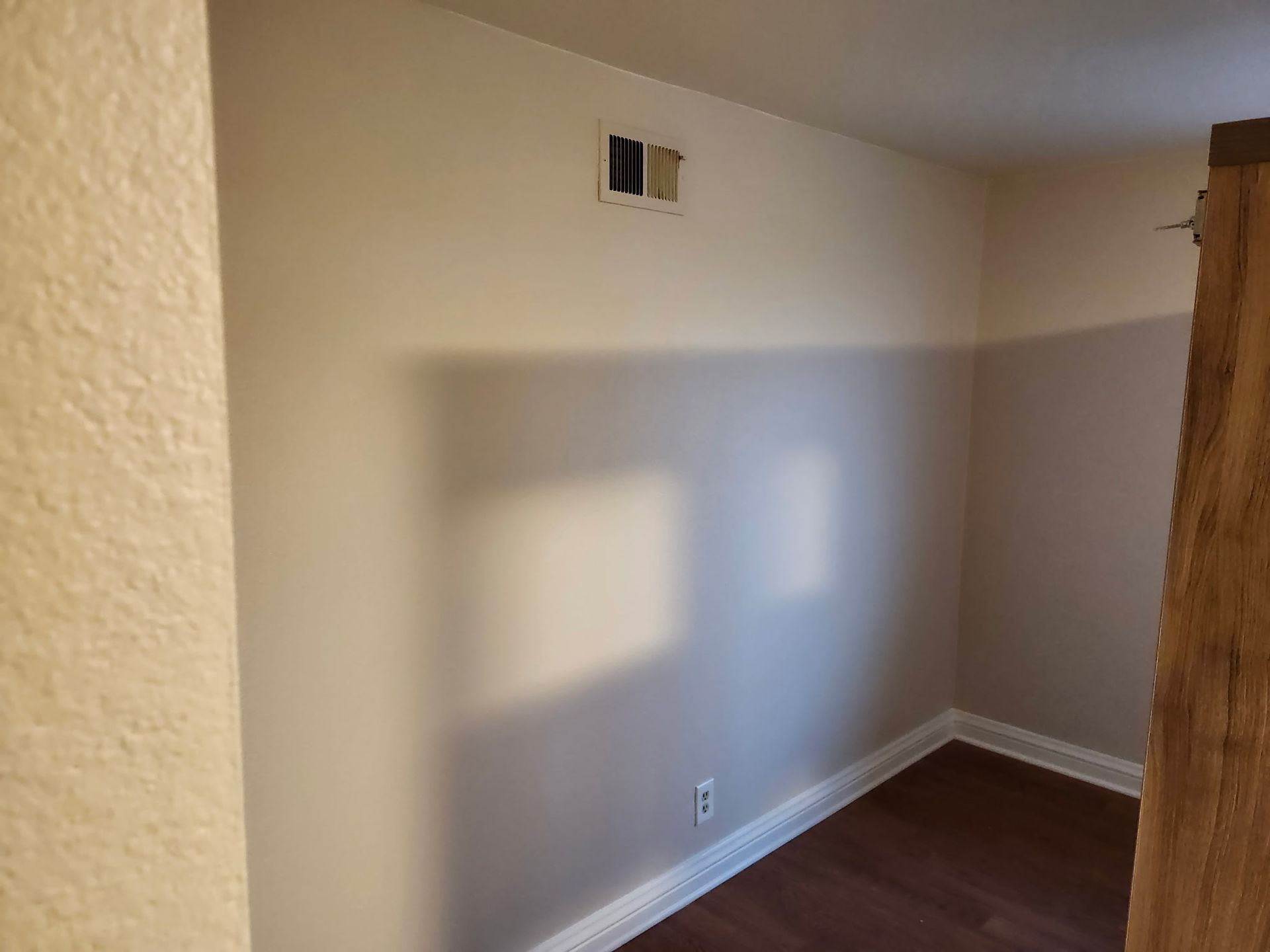 Empty room with two-tone painted walls, dark flooring, and a vent near the ceiling.